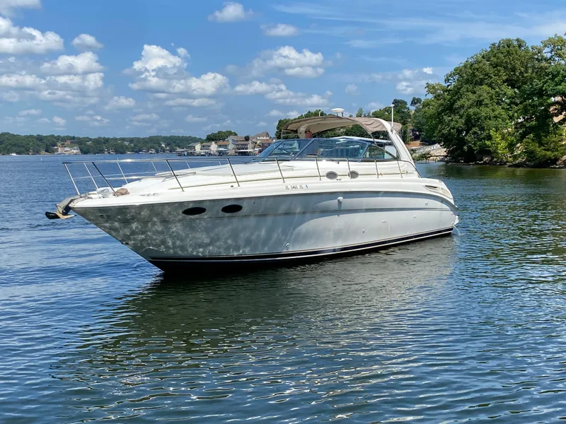 Slide: The Image of 1999 Sea Ray 380 Sundancer yacht on a serene lake under a blue sky. - 5