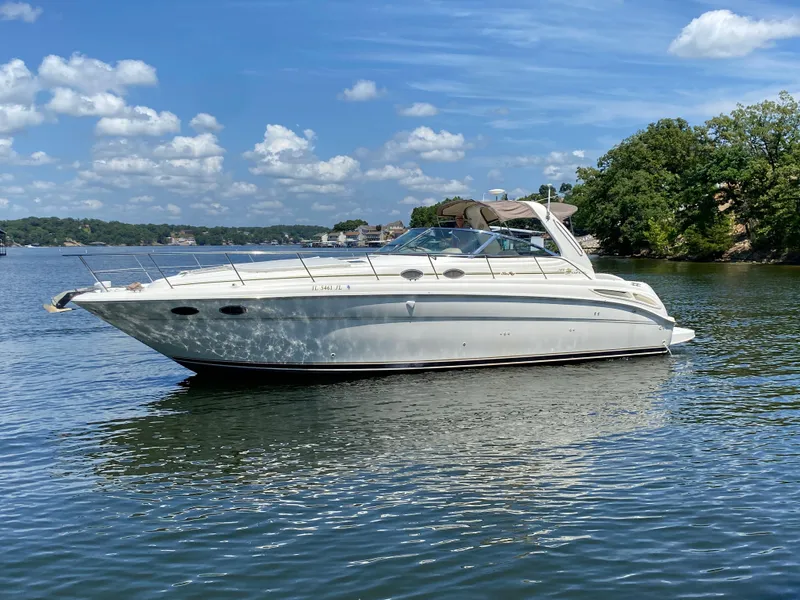 Slide: The Image of 1999 Sea Ray 380 Sundancer yacht on a serene lake under a blue sky. - 6