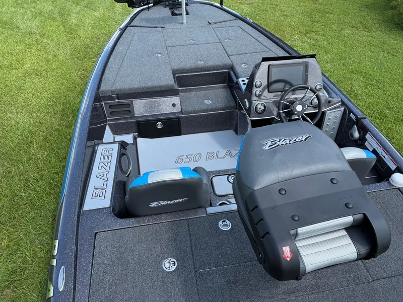 Slide: The Image of 2026 Blazer 650 NAP boat interior with steering console and seating on grass. - 11