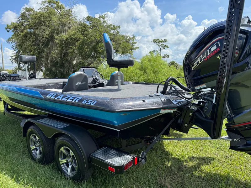 Slide: The Image of 2026 Blazer 650 NAP boat on grass, featuring dual axles and powerful outboard motor. - 15