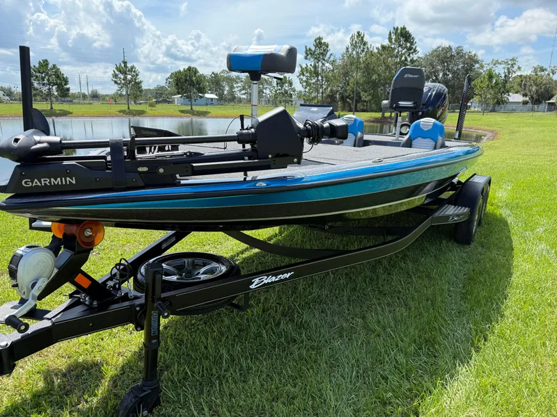 Slide: The Image of 2026 Blazer 650 NAP boat on trailer, featuring Garmin equipment, parked on grass by a pond. - 4