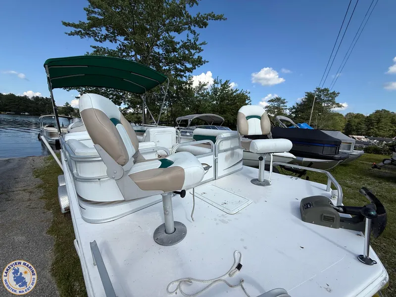 Slide: The Image of 2005 Hurricane FunDeck 226 REF boat with seating, docked by a lake under a clear sky. - 3