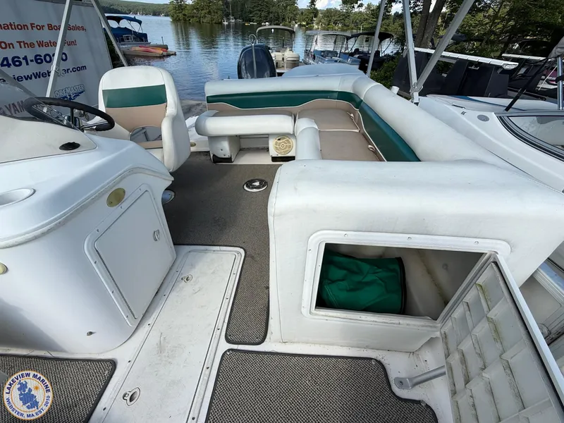 Slide: The Image of 2005 Hurricane FunDeck 226 REF interior with seating and storage, docked by a serene lake. - 9