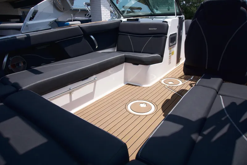 Slide: The Image of 2021 MasterCraft XT22 boat interior with sleek black seating and teak-style flooring. - 13