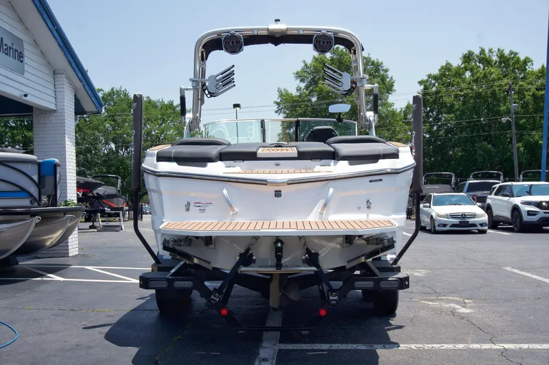 Slide: The Image of 2021 MasterCraft XT22 boat on trailer, parked at a dealership, surrounded by cars and trees. - 3