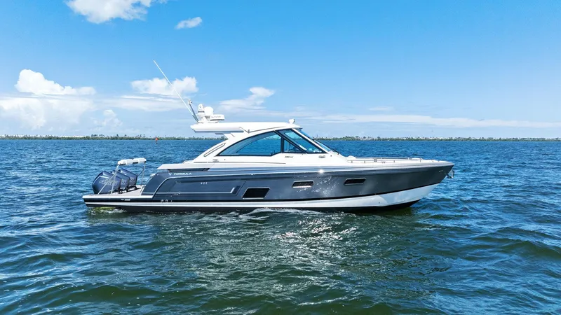 The Image of 2023 Formula 380 Super Sport Crossover OB cruising on open water under clear blue skies. - 0