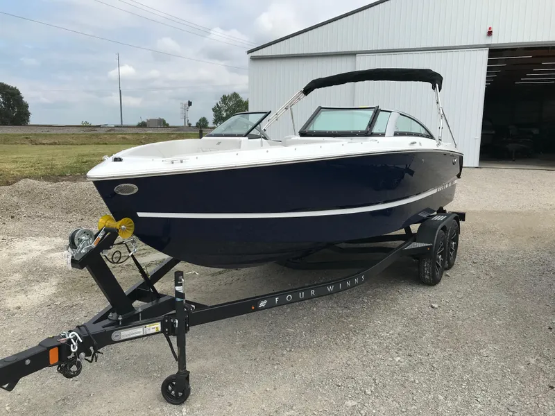 Slide: The Image of 2026 Four Winns H-1 FREEDOM boat on trailer near a warehouse. - 10