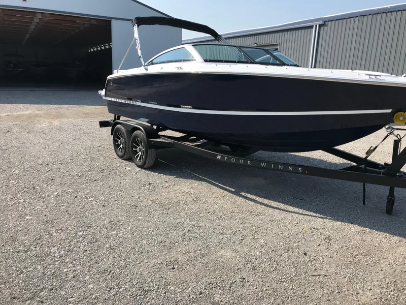 Slide: The Image of 2026 Four Winns H-1 FREEDOM boat on trailer, parked outside a storage facility. - 25