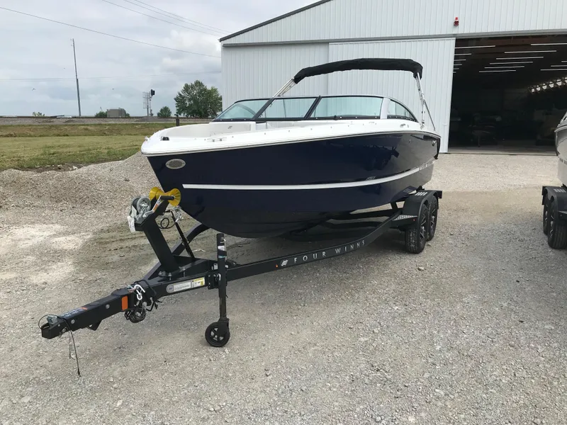 Slide: The Image of 2026 Four Winns H-1 FREEDOM boat on trailer outside a large garage. - 7