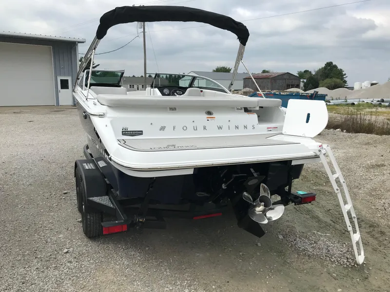 Slide: The Image of 2026 Four Winns H-1 FREEDOM boat on trailer, rear view with ladder and propeller. - 9