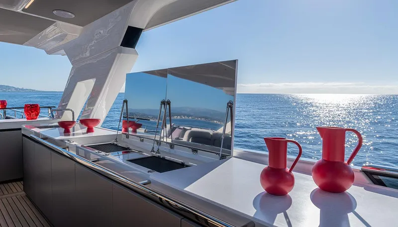 Slide: The Image of Luxurious Absolute NAVETTA 75 yacht kitchen with ocean view, featuring red pitchers and modern design. - 21