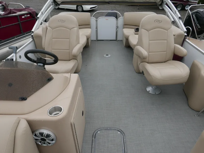 Slide: The Image of 2017 Manitou Aurora VP pontoon boat interior with beige seating and steering console. - 10