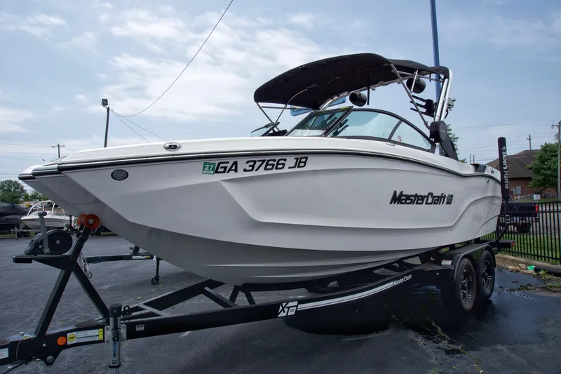 Slide: The Image of 2022 MasterCraft XT22 boat on trailer, displayed outdoors. - 2