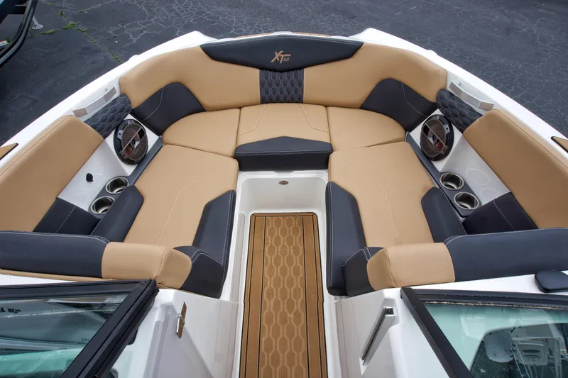 Slide: The Image of 2022 MasterCraft XT22 boat interior with tan and black seating, cup holders, and speakers. - 7