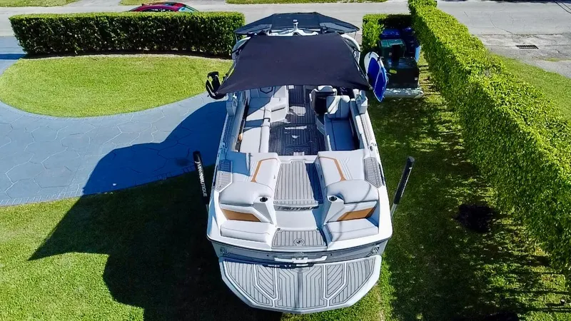 Slide: The Image of 2020 Nautique Super Air Nautique G25 Coastal Edition boat with canopy, parked on grass. - 2