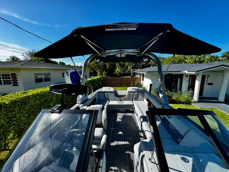 Slide: The Image of 2020 Nautique Super Air Nautique G25 Coastal Edition boat with canopy, parked in residential area. - 23