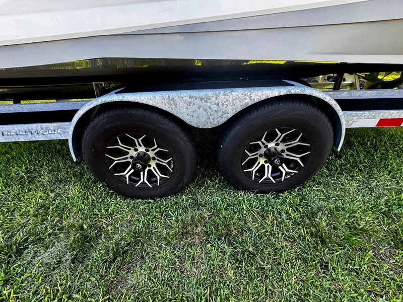 Slide: The Image of Trailer wheels of a 2020 Nautique Super Air Nautique G25 Coastal Edition on grass. - 31