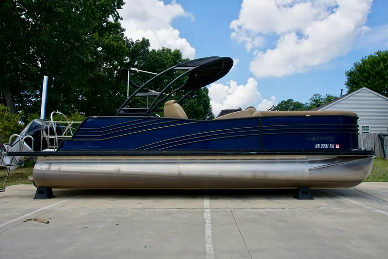 The Image of 2020 Harris Grand Mariner 230 pontoon boat on a driveway, under a blue sky. - 0