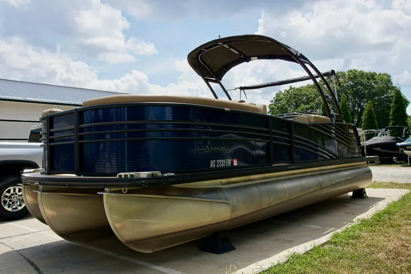 Slide: The Image of 2020 Harris Grand Mariner 230 pontoon boat parked outdoors under cloudy sky. - 2