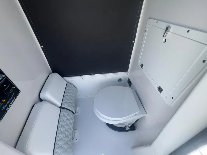 Slide: The Image of 2026 Blackfin 262 HB boat interior with compact marine toilet and cushioned seating. - 28
