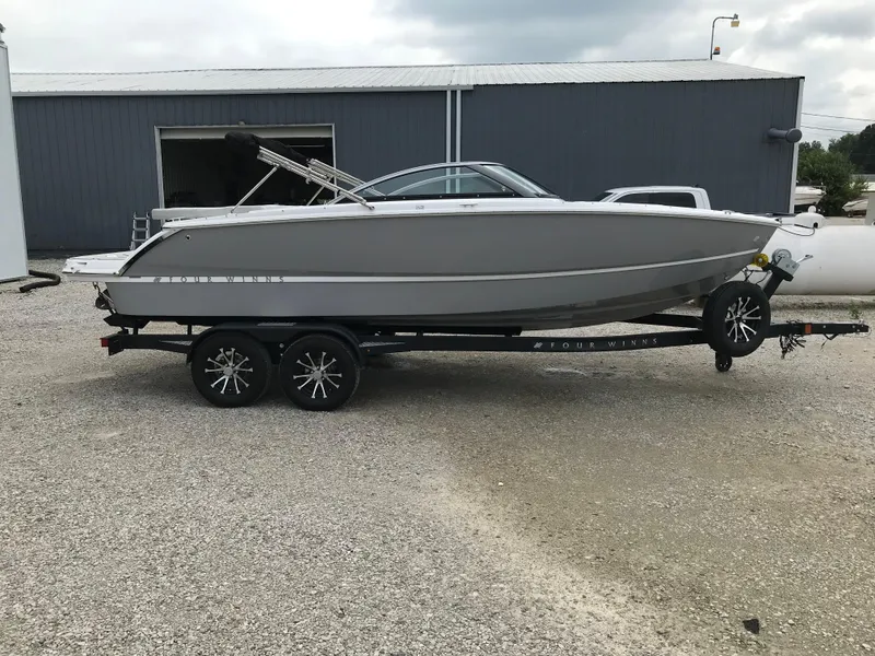 The Image of 2026 Four Winns H-2 FREEDOM boat on trailer, parked outside a warehouse. - 2
