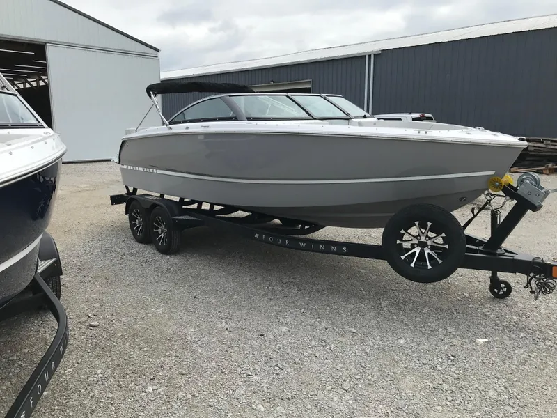 Slide: The Image of 2026 Four Winns H-2 FREEDOM boat on trailer, parked outside a warehouse. - 4