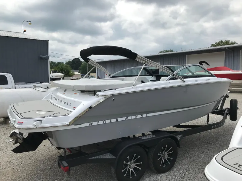 Slide: The Image of 2026 Four Winns H-2 Freedom boat on trailer, parked outdoors under cloudy sky. - 7