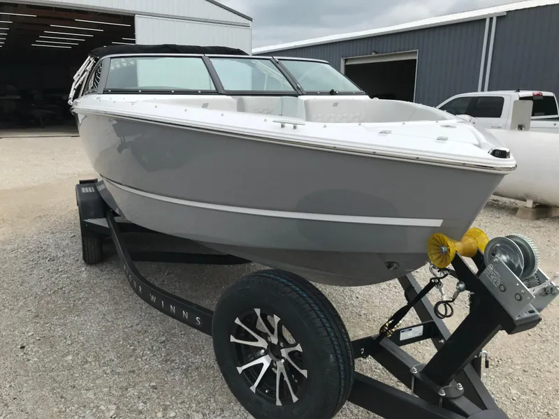 Slide: The Image of 2026 Four Winns H-2 FREEDOM boat on trailer, parked outside a warehouse. - 8