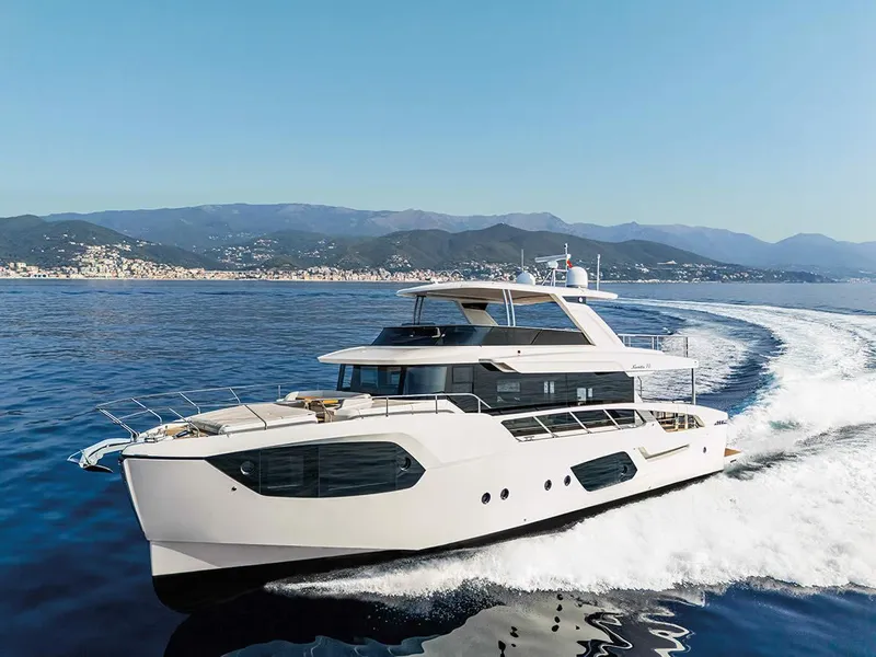 The Image of Luxurious 2026 Absolute NAVETTA 70 yacht cruising on open sea with scenic mountain backdrop. - 0