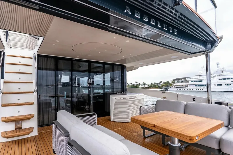 Slide: The Image of Luxurious Absolute NAVETTA 70 yacht deck with modern seating, glass doors, and scenic waterfront view. - 13