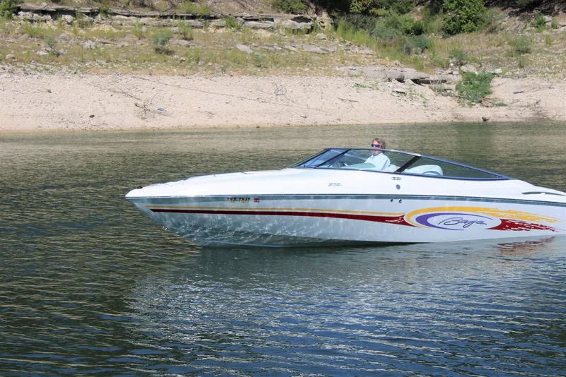 Slide: The Image of 2002 Baja 232 speedboat on calm water near a rocky shoreline. - 11