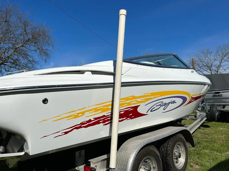 Slide: The Image of 2002 Baja 232 speedboat on trailer with vibrant graphics, parked outdoors. - 14