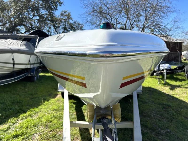 Slide: The Image of 2002 Baja 232 boat on trailer, parked outdoors, with colorful stripes and clear sky background. - 17