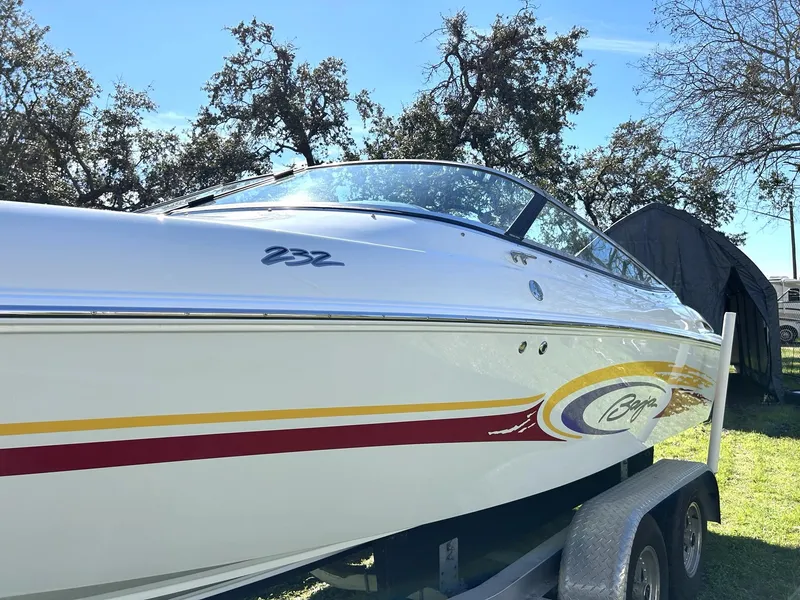 Slide: The Image of 2002 Baja 232 speedboat on trailer, white with colorful graphics, parked outdoors. - 19