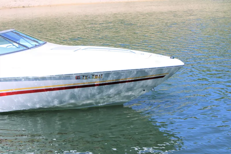 Slide: The Image of 2002 Baja 232 boat on calm water, featuring sleek design and vibrant stripes. - 2