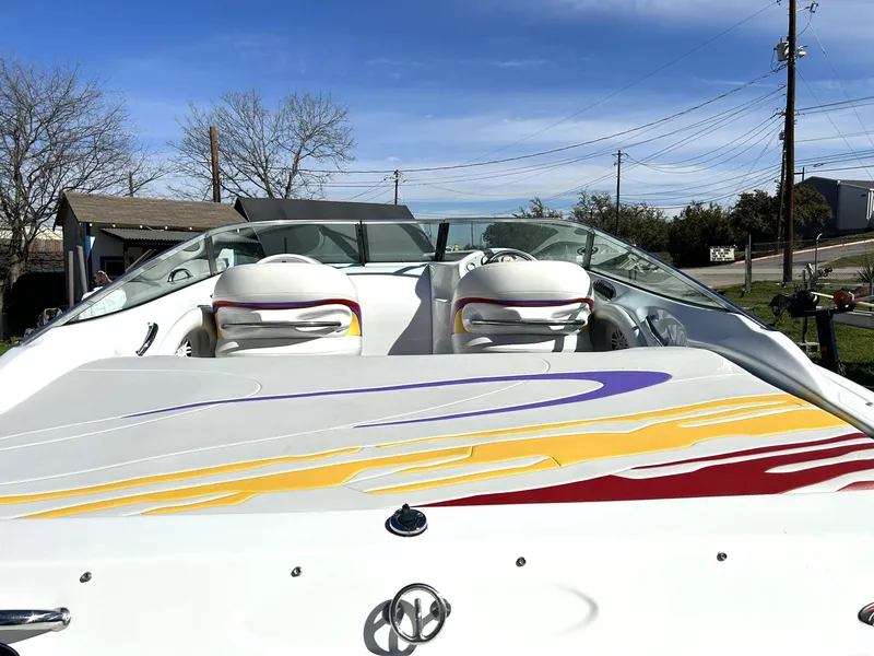 Slide: The Image of 2002 Baja 232 boat with colorful graphics, parked outdoors under a clear blue sky. - 26