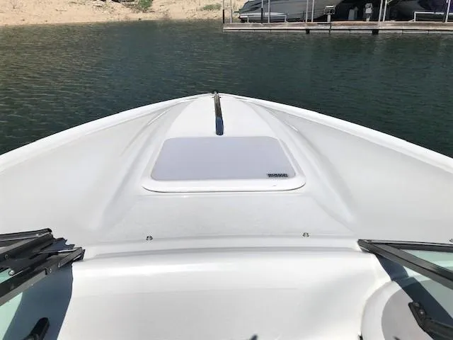 Slide: The Image of Bow view of a 2002 Baja 232 boat on calm water near a dock. - 29