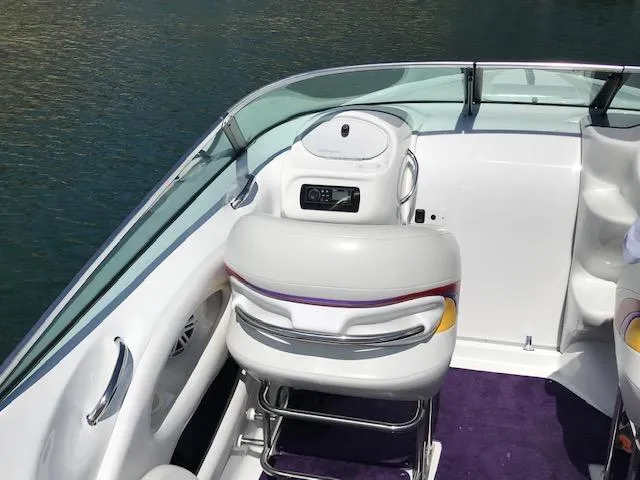 Slide: The Image of 2002 Baja 232 boat interior with white seating and purple carpet, docked on calm water. - 39