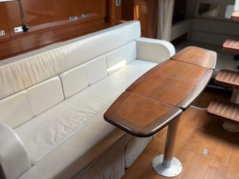Slide: The Image of Interior of a 2012 Sea Ray 350 Sundancer with a wooden table and white leather seating. - 23