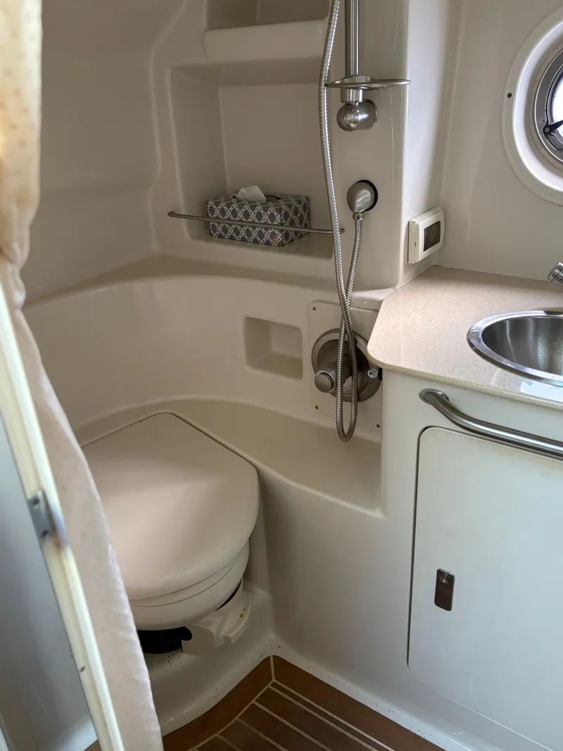 Slide: The Image of 2012 Sea Ray 350 Sundancer bathroom with toilet, sink, and showerhead. - 24