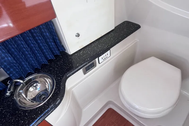 Slide: The Image of 2008 Formula 310 Bowrider bathroom with sink, toilet, and blue curtain. - 14
