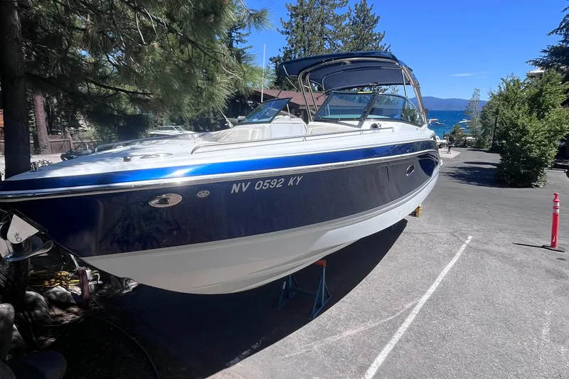 Slide: The Image of 2008 Formula 310 Bowrider boat on trailer, parked near trees and lake. - 2