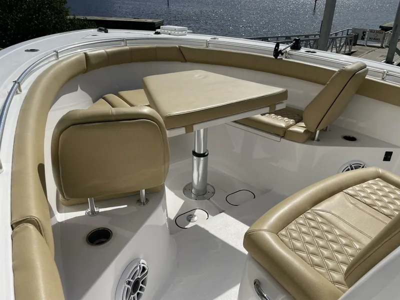 Slide: The Image of 2021 Sportsman 302 OPEN boat interior with tan seating and table, docked by the water. - 12