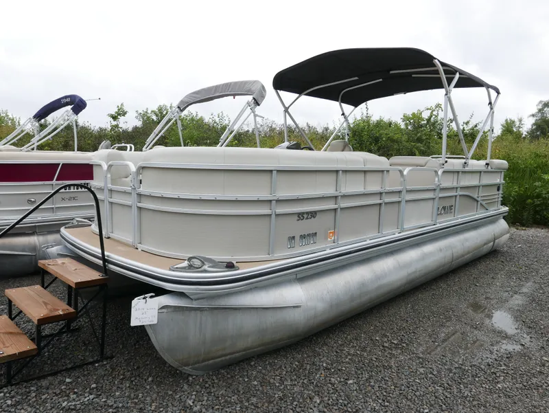 Slide: The Image of 2015 Lowe SS230 pontoon boat with canopy, parked on gravel. - 2