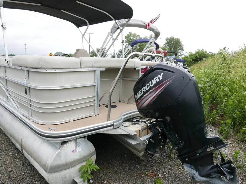 Slide: The Image of 2015 Lowe SS230 pontoon boat with Mercury outboard motor, parked on gravel near greenery. - 3