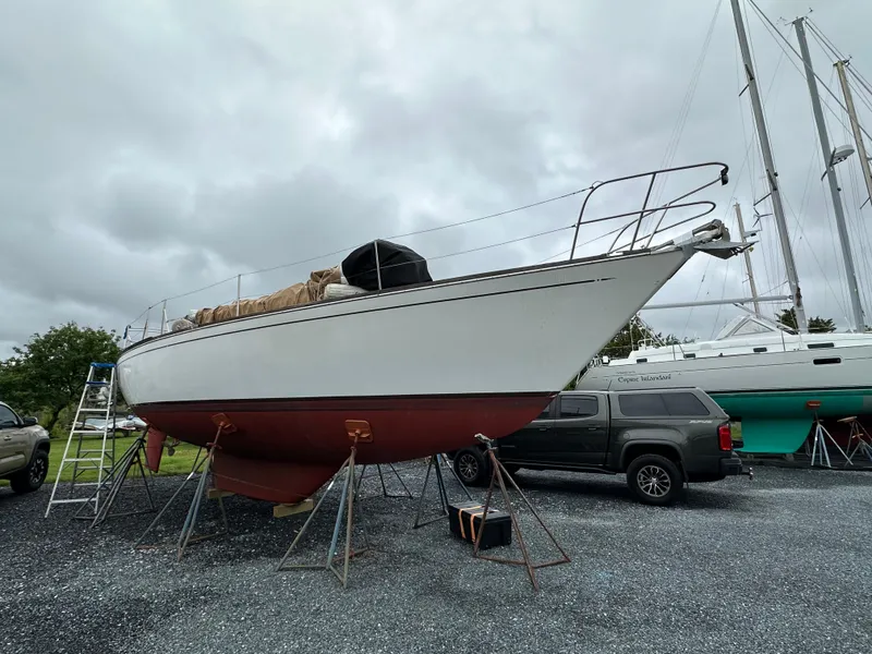 Slide: The Image of 1981 Tartan 37 sloop on stands, overcast sky, parked truck nearby. - 3