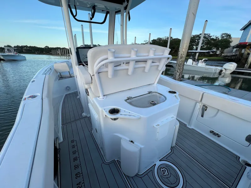 Slide: The Image of 2024 Sea Hunt Ultra 239 SE boat interior with rod holders and seating, docked by the water. - 12