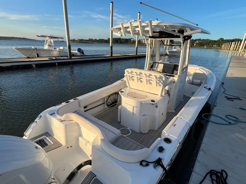 Slide: The Image of 2024 Sea Hunt Ultra 239 SE boat docked at marina, showcasing spacious deck and seating. - 6