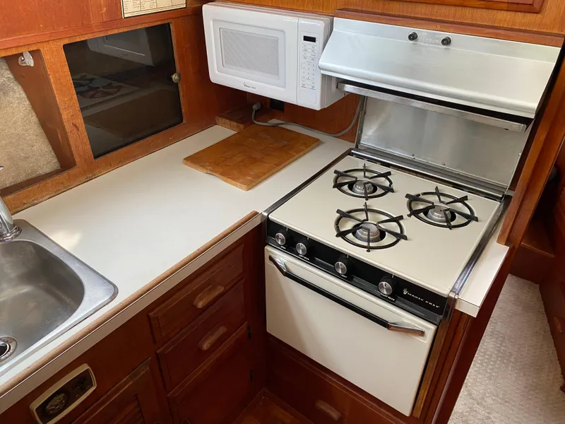 Slide: The Image of 1984 Tollycraft 34 Convertible Sedan kitchen with stove, microwave, and sink. - 10