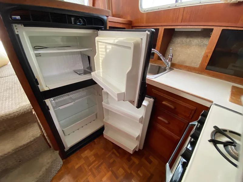 Slide: The Image of 1984 Tollycraft 34 Convertible Sedan kitchen with open fridge, sink, and stove. - 12